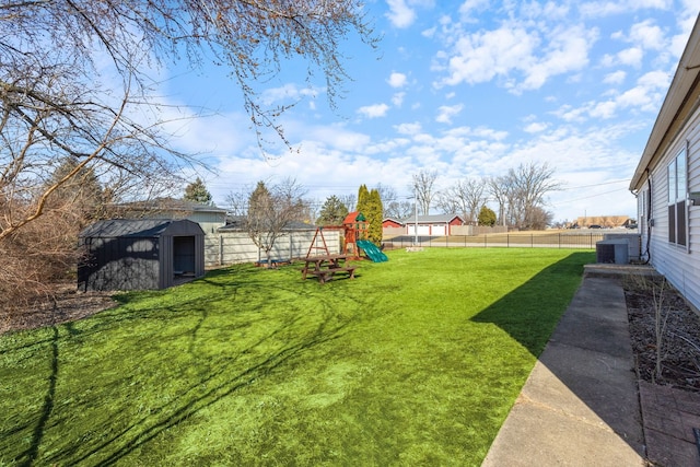 view of yard featuring an outbuilding, central AC, a fenced backyard, a playground, and a storage shed