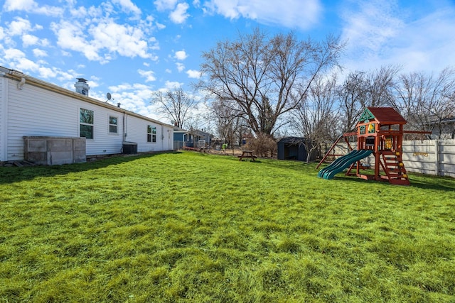 view of yard featuring an outbuilding, a shed, a playground, and fence