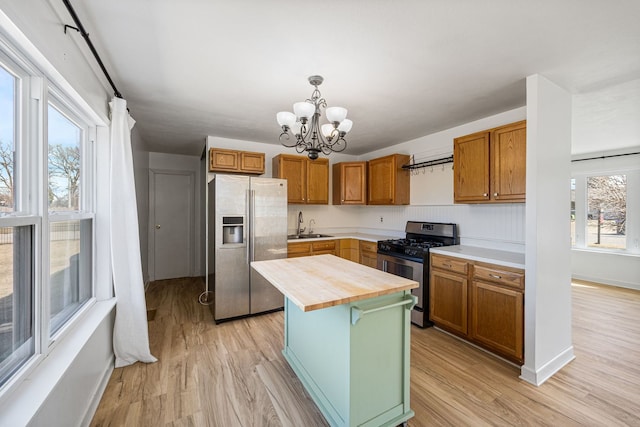 kitchen with light wood finished floors, butcher block countertops, stainless steel appliances, and a sink