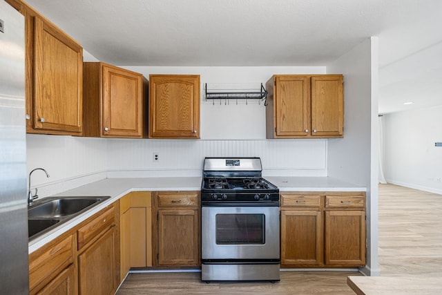 kitchen featuring a sink, stainless steel appliances, light wood-type flooring, and light countertops