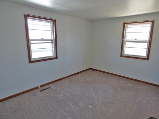 carpeted empty room with visible vents and baseboards