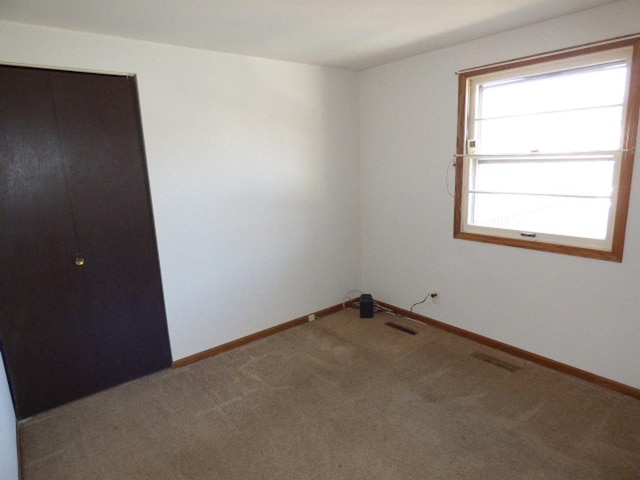 unfurnished room with visible vents, baseboards, and carpet floors