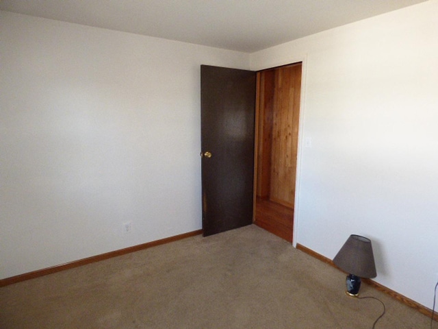 unfurnished room with light colored carpet and baseboards