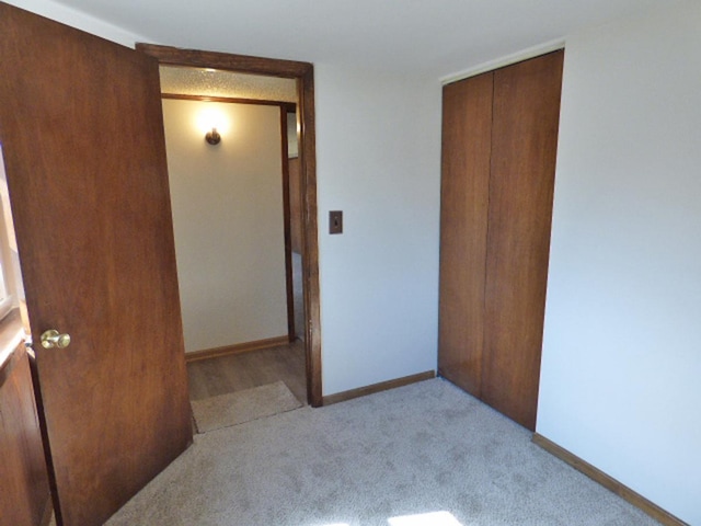 unfurnished bedroom featuring a closet, baseboards, and carpet floors