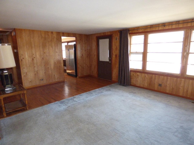 unfurnished living room featuring wooden walls and carpet floors