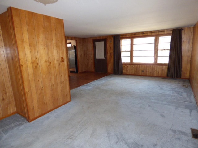 carpeted spare room featuring wood walls