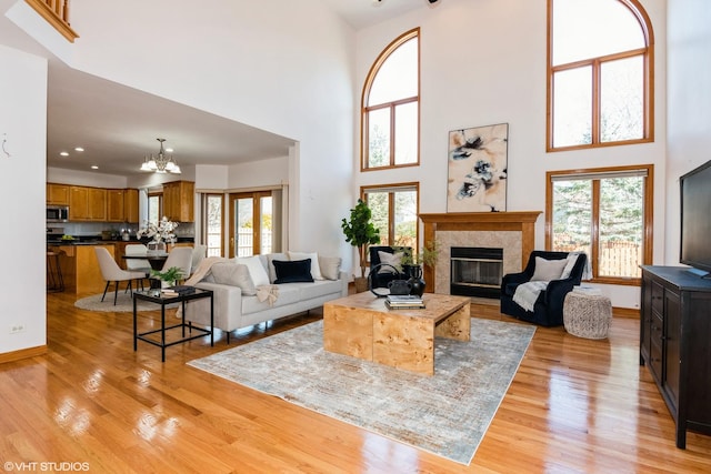 living area with a notable chandelier, light wood-style flooring, plenty of natural light, and a fireplace