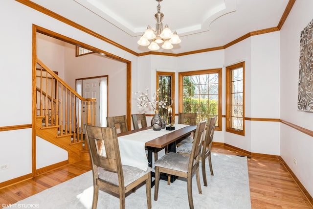 dining space featuring baseboards, a chandelier, stairway, wood finished floors, and a raised ceiling