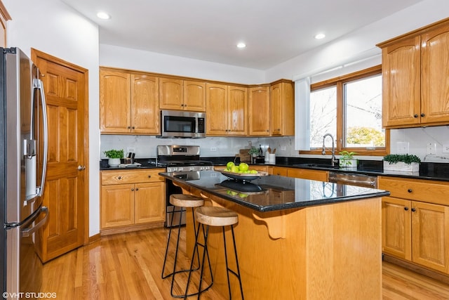 kitchen featuring a sink, a breakfast bar area, light wood-style floors, and stainless steel appliances