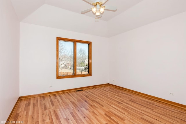 spare room featuring visible vents, a ceiling fan, a tray ceiling, light wood-style floors, and baseboards