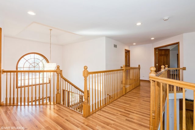 hall featuring wood finished floors, visible vents, baseboards, recessed lighting, and an upstairs landing