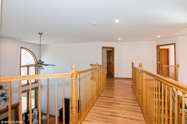 corridor with an upstairs landing, recessed lighting, and light wood finished floors