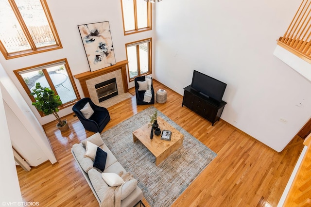 living room featuring plenty of natural light, a fireplace, a high ceiling, and wood finished floors