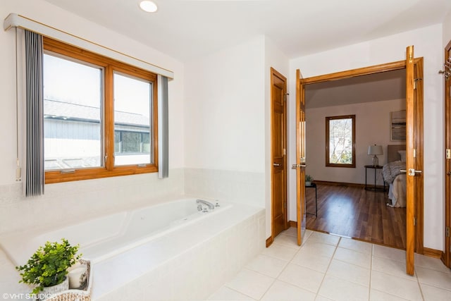 ensuite bathroom featuring tile patterned floors, baseboards, a garden tub, and ensuite bathroom