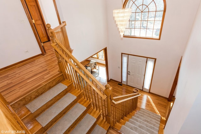 entrance foyer with stairway, wood finished floors, a high ceiling, and baseboards