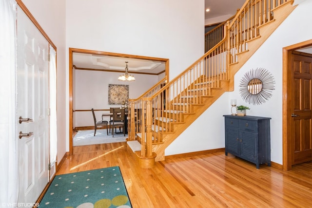 entrance foyer with baseboards, stairway, ornamental molding, an inviting chandelier, and wood finished floors