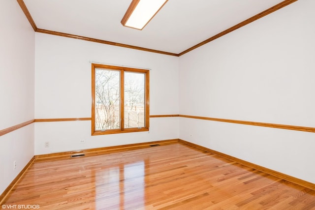 unfurnished room with visible vents, baseboards, crown molding, and light wood finished floors