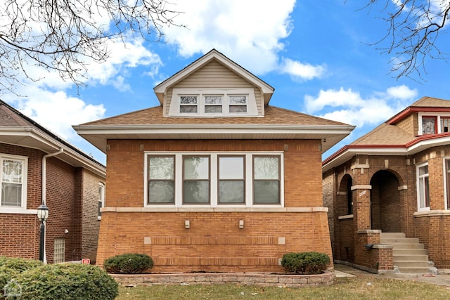 bungalow with brick siding and a shingled roof