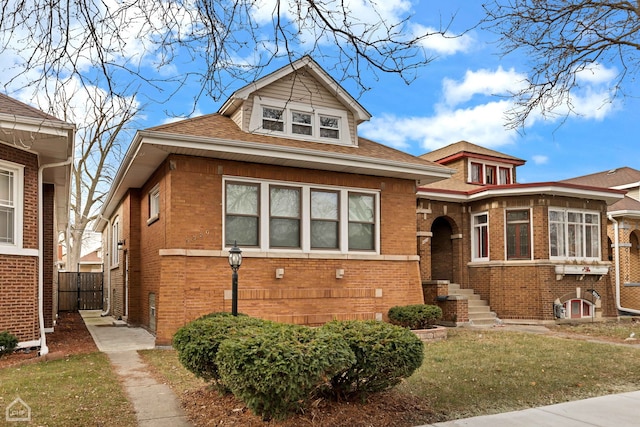 bungalow featuring brick siding, a shingled roof, and fence