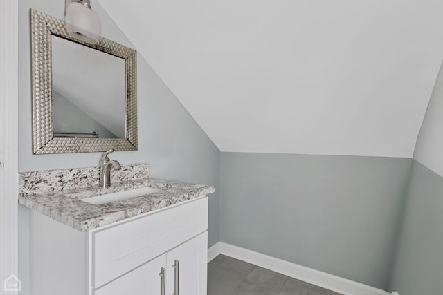 bathroom with vanity, vaulted ceiling, and baseboards