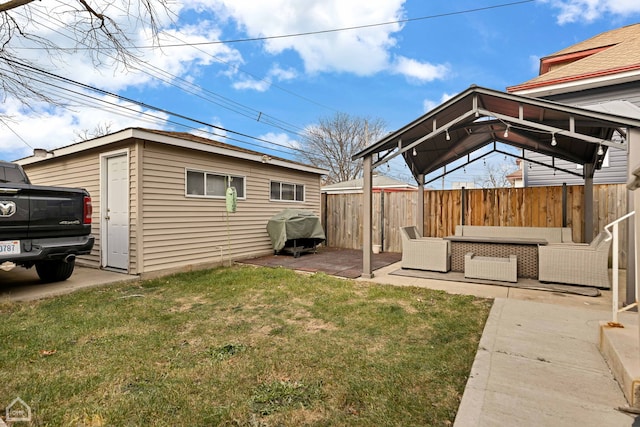 view of yard featuring an outbuilding, an outdoor living space, fence, a gazebo, and a patio area