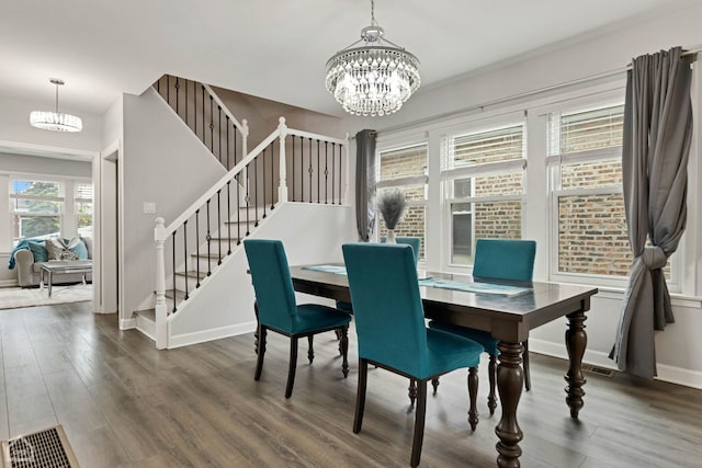 dining room featuring visible vents, wood finished floors, baseboards, a chandelier, and stairs