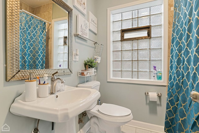 full bath with a wealth of natural light, tile patterned floors, toilet, and a sink