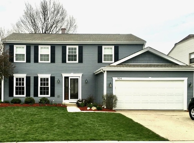 colonial house with a front yard, roof with shingles, driveway, a chimney, and a garage