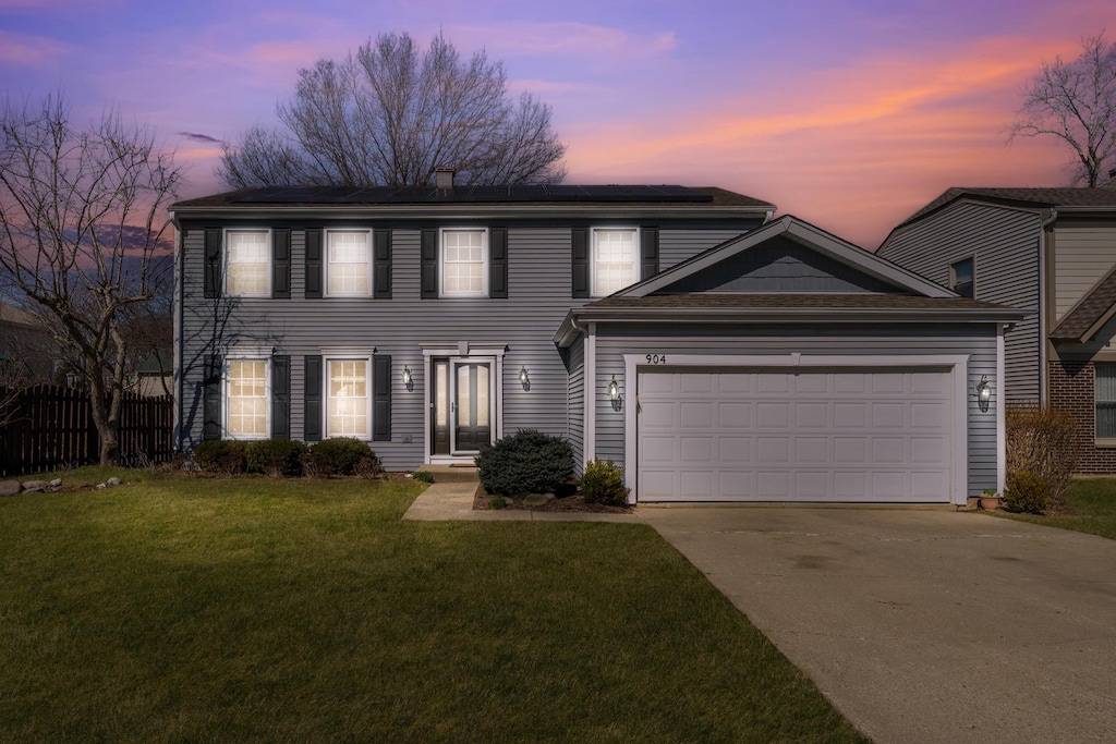 904 Dannet Rd, Buffalo Grove, IL 60089 - colonial-style house with roof mounted solar panels, fence, a yard, concrete driveway, and a garage