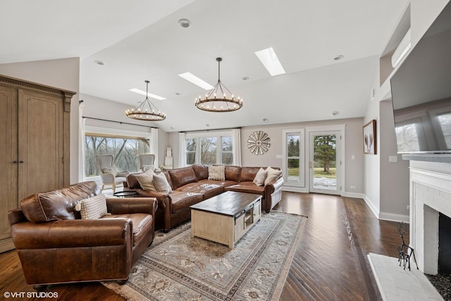 living room featuring a healthy amount of sunlight, an inviting chandelier, and lofted ceiling with skylight