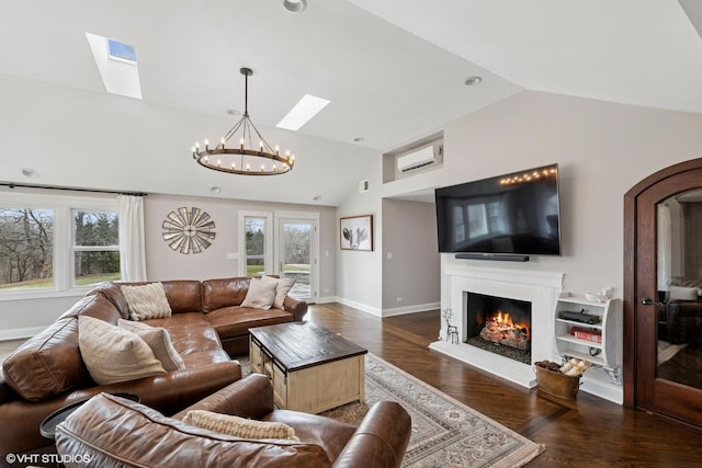 living area featuring vaulted ceiling with skylight, a healthy amount of sunlight, a chandelier, and a wall mounted air conditioner