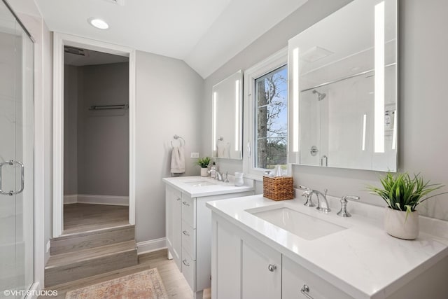 bathroom featuring a shower stall, wood finished floors, a sink, and vaulted ceiling