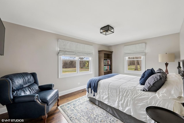 bedroom featuring baseboards, multiple windows, and wood finished floors