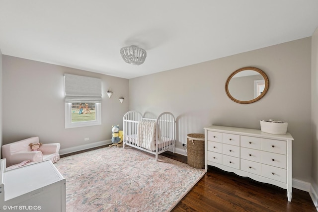 bedroom featuring dark wood-type flooring, baseboards, and a nursery area