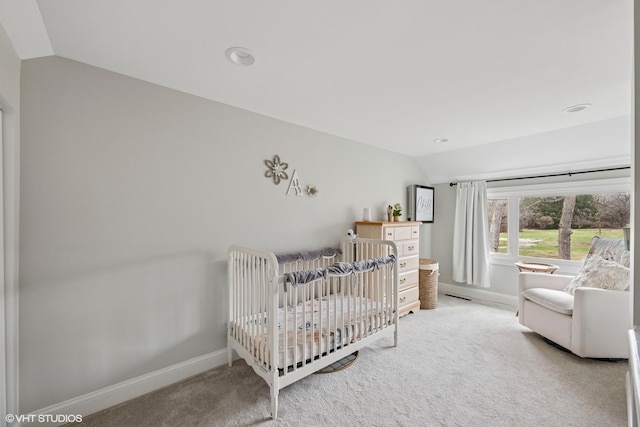 bedroom featuring light carpet, baseboards, vaulted ceiling, and a crib