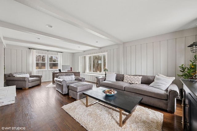 living area with dark wood-style flooring, beam ceiling, and a decorative wall