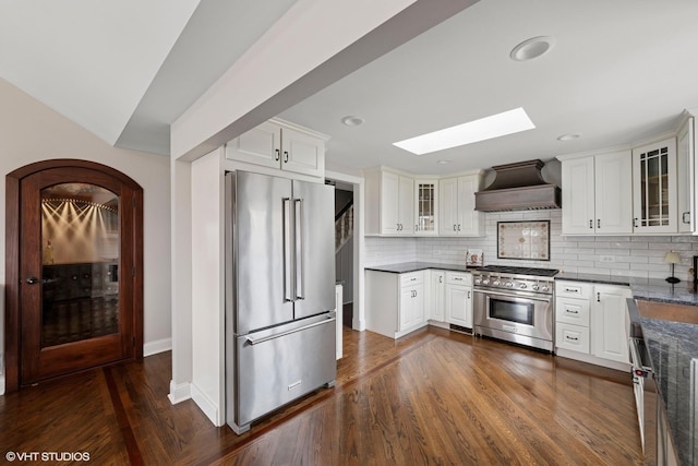 kitchen with custom range hood, high end appliances, decorative backsplash, and a skylight