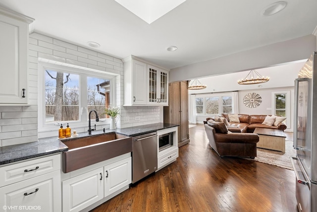 kitchen featuring glass insert cabinets, dark wood-type flooring, a sink, stainless steel appliances, and a notable chandelier