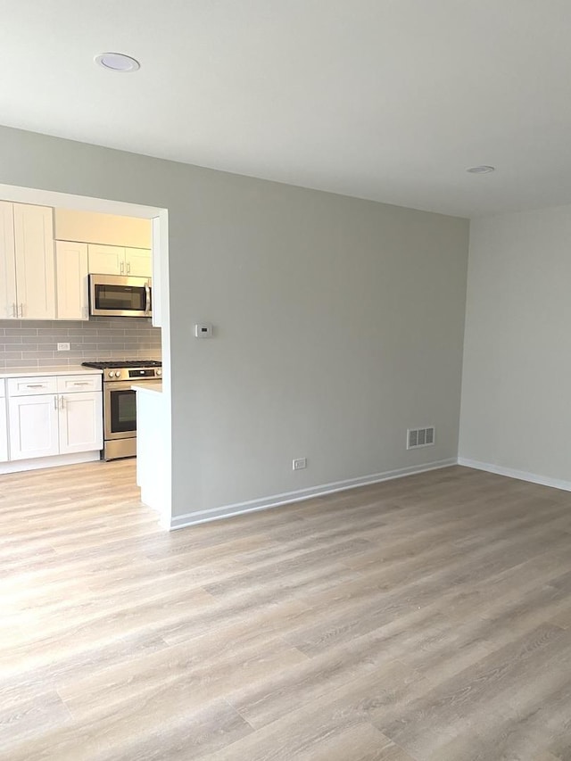 unfurnished living room with visible vents, baseboards, and light wood-style floors