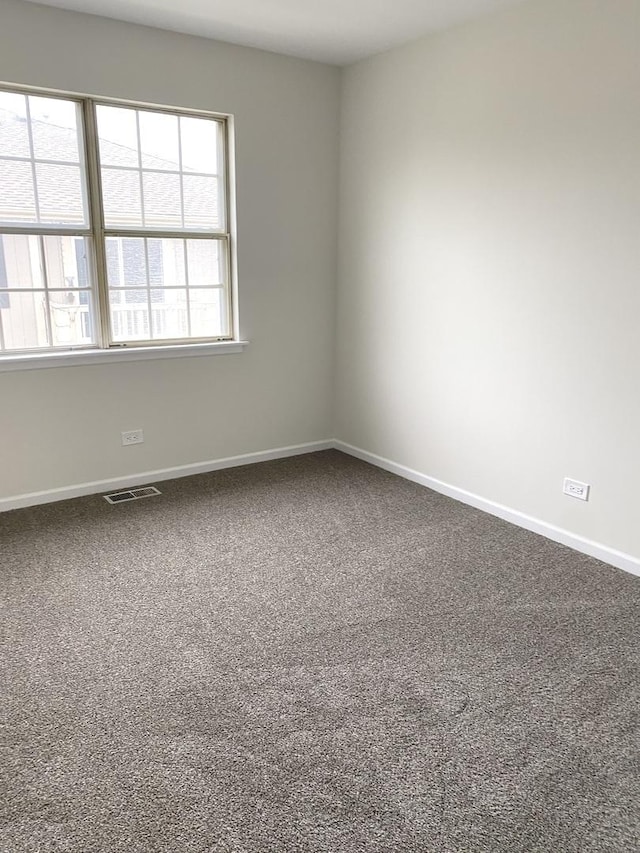 unfurnished room with visible vents, baseboards, and dark carpet