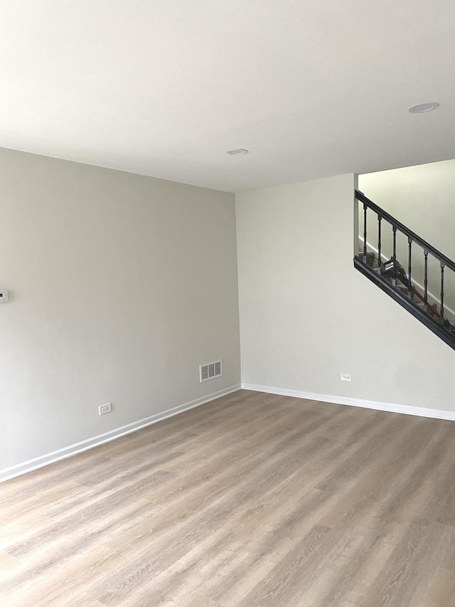 empty room featuring visible vents, baseboards, wood finished floors, and stairway