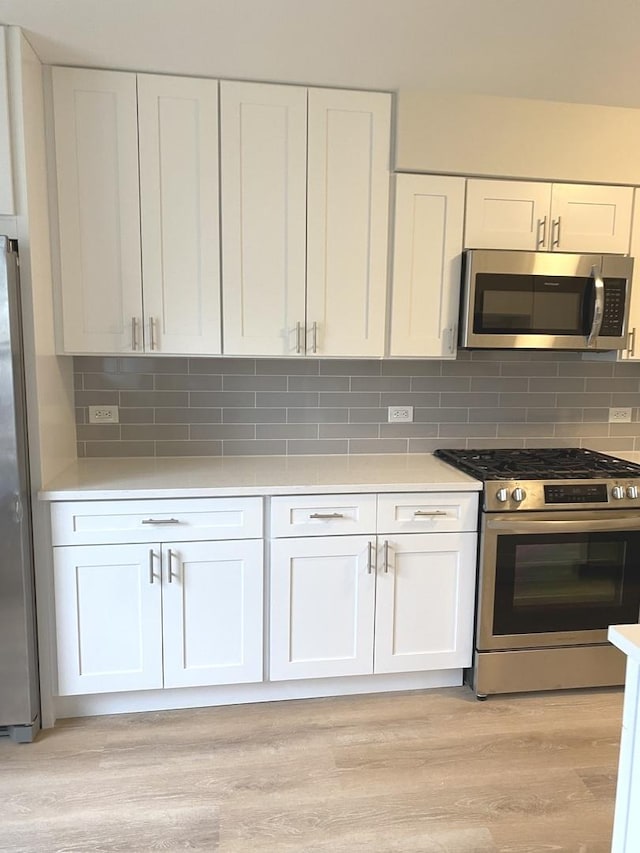 kitchen featuring backsplash, white cabinets, appliances with stainless steel finishes, and light wood-style floors