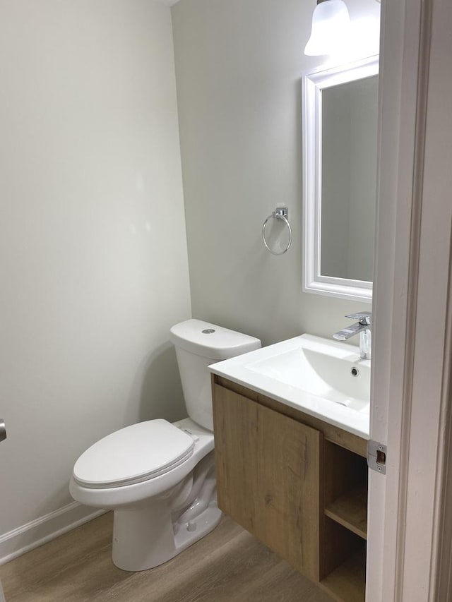 bathroom featuring toilet, vanity, baseboards, and wood finished floors