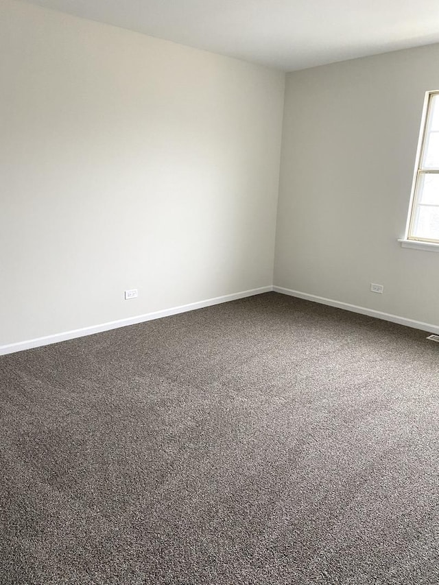 empty room featuring carpet and baseboards