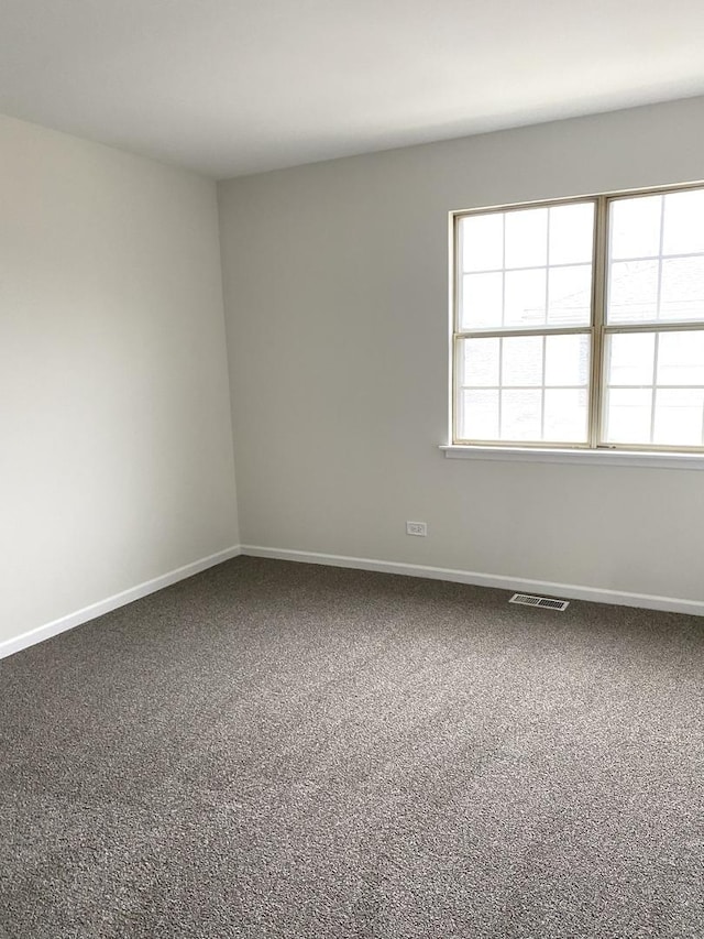 carpeted empty room featuring visible vents and baseboards