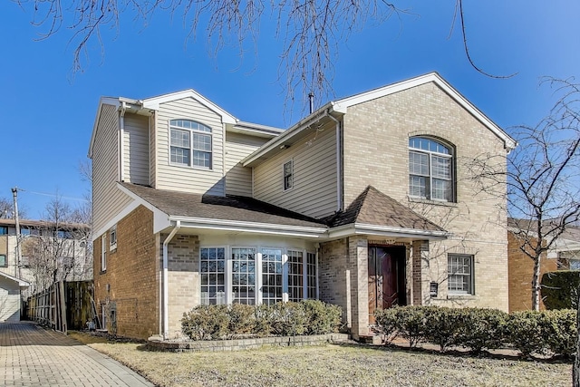 traditional home with brick siding and a shingled roof