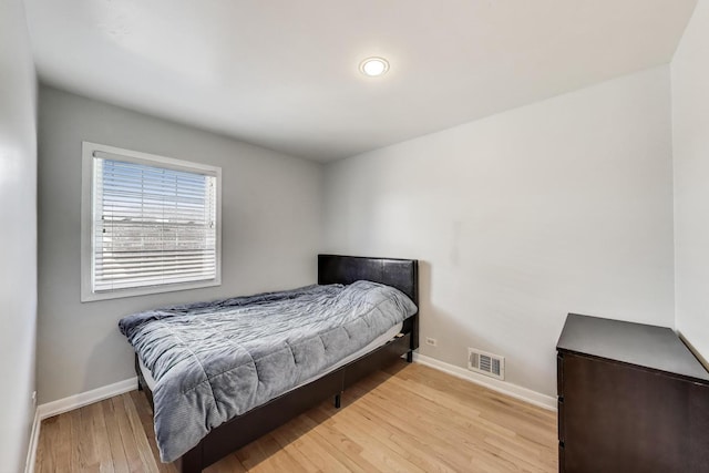 bedroom with visible vents, light wood-style flooring, and baseboards