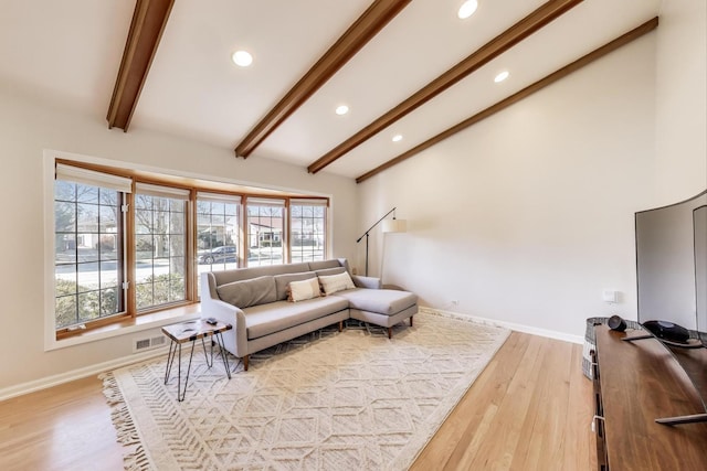 living area with visible vents, beamed ceiling, light wood-style floors, and baseboards