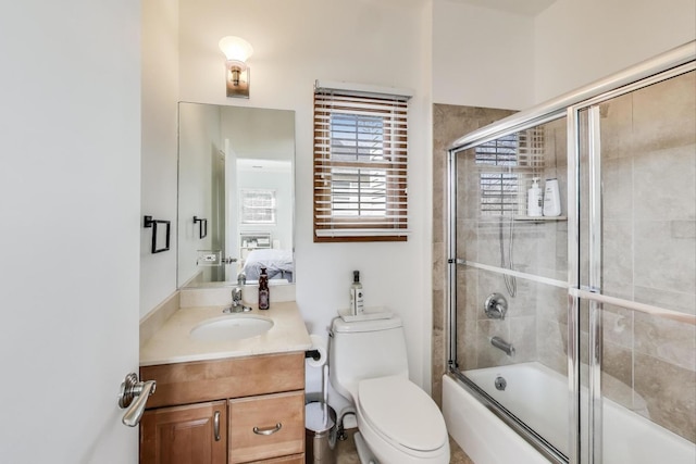 ensuite bathroom featuring ensuite bathroom, bath / shower combo with glass door, vanity, and toilet