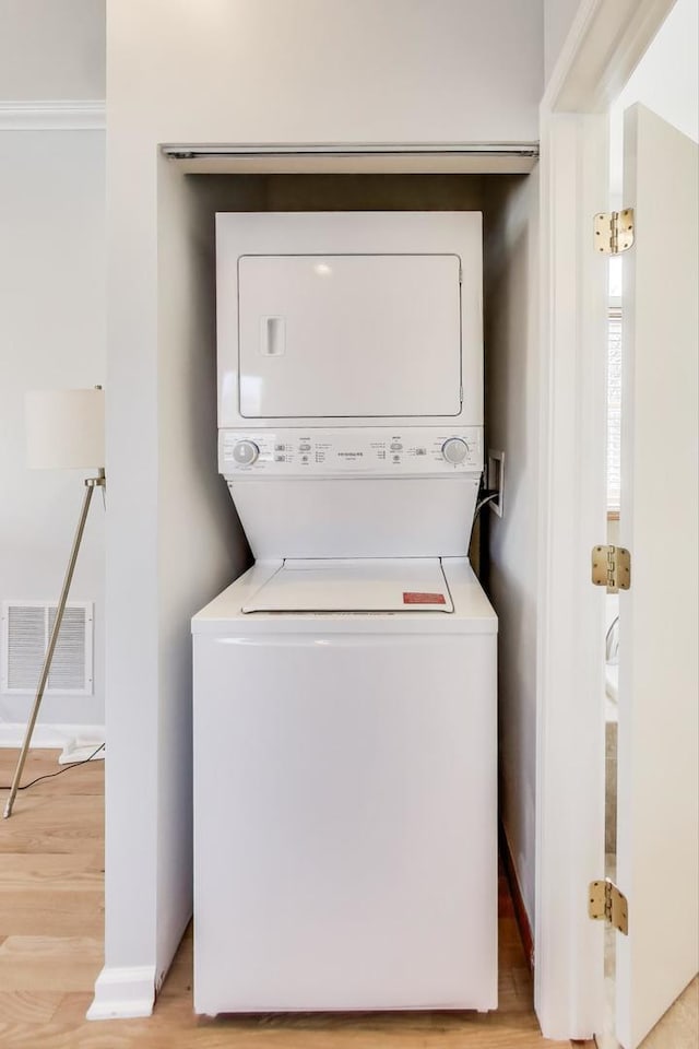 laundry room with laundry area, light wood finished floors, visible vents, and stacked washer and clothes dryer